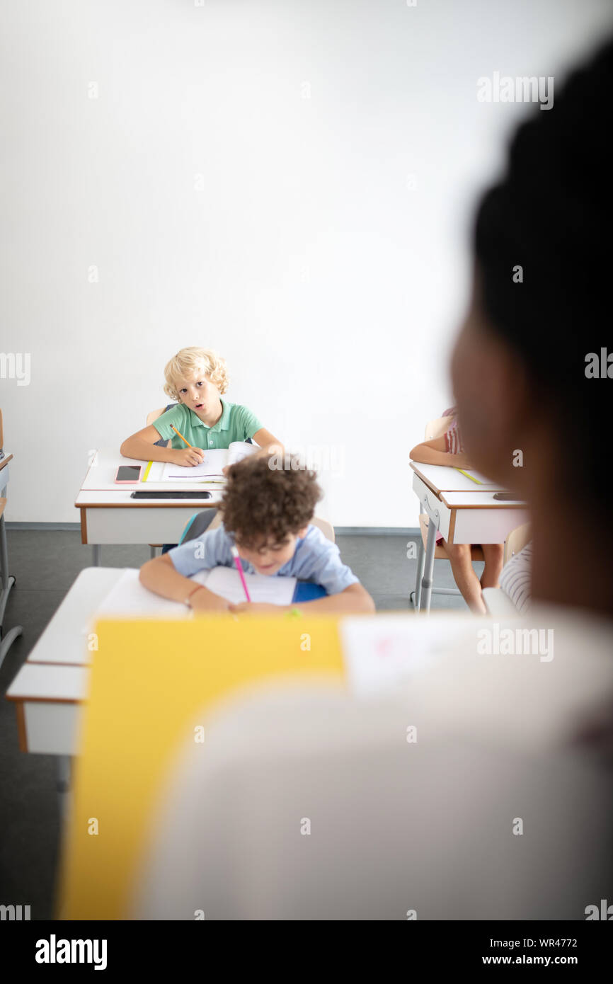 Notant les enfants vers le bas lors de l'écoute à l'enseignant Banque D'Images