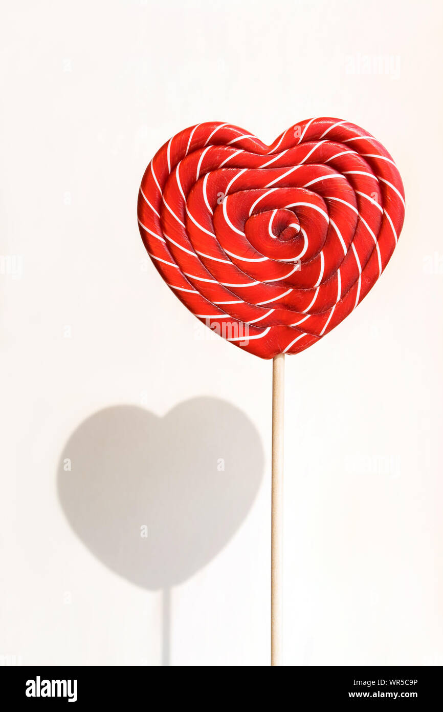 Sweet Heart shaped lollipop sur mur blanc arrière-plan avec l'ombre. Banque D'Images