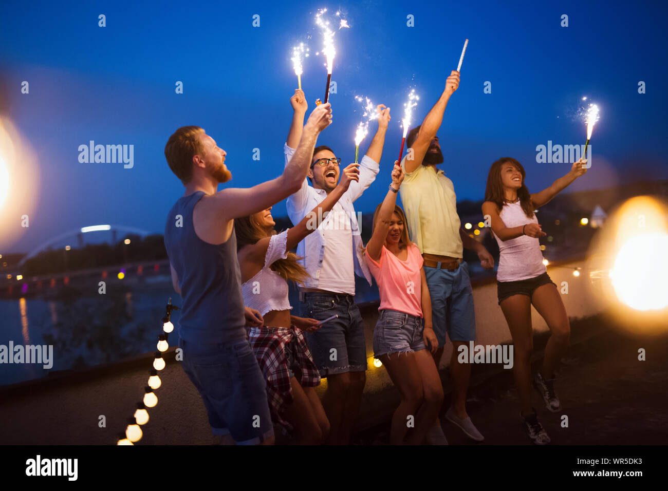 Friends enjoying a rooftop party et danse avec les cierges magiques Banque D'Images