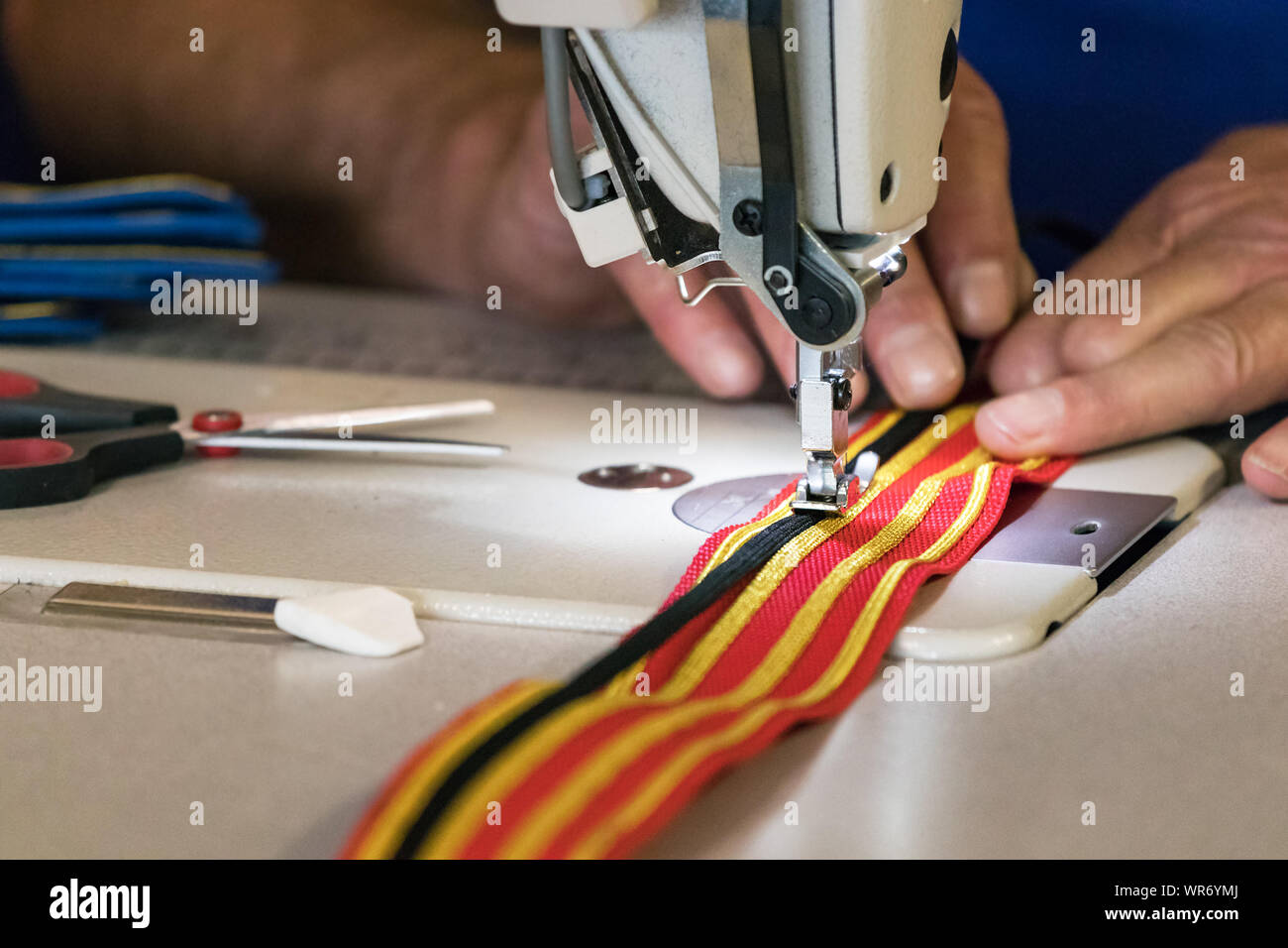 Couture à la main mâle golden et bandes noires sur un costume rouge belt à Belfast, en Irlande, au Royaume-Uni. Banque D'Images