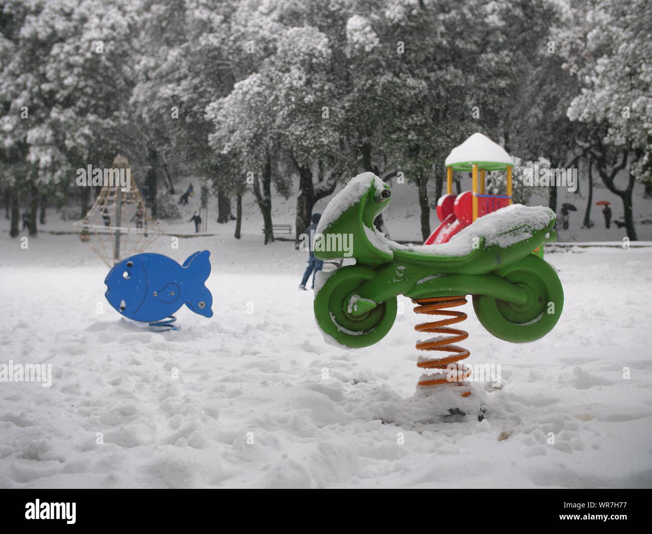 En ressort couvert de neige dans des jeux pour les enfants. Forme de  poisson et de moto. Vert, Orange et bleu Photo Stock - Alamy