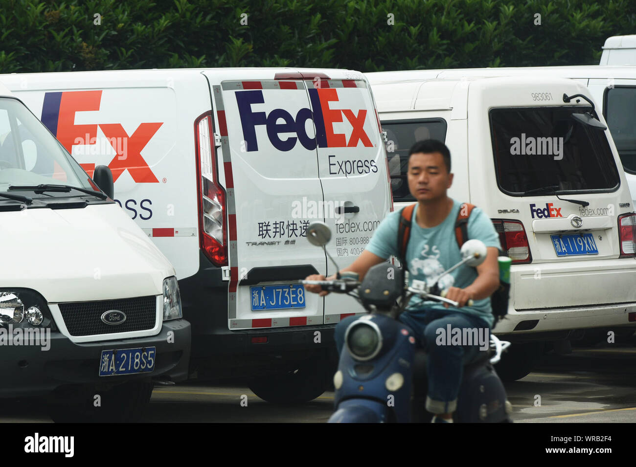 Un cycliste chinois chevauche son vélo électrique les véhicules de livraison d'envois FedEx Express dans la rue dans la ville de Hangzhou, Zhejiang Province de Chine orientale, Juillet Banque D'Images