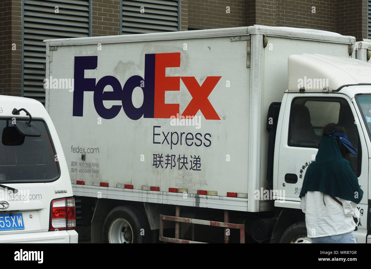 Un piéton chinois passe devant les véhicules de livraison de FedEx Express sur la rue dans la ville de Hangzhou, Zhejiang Province de Chine orientale, le 26 juillet, 2019. Banque D'Images