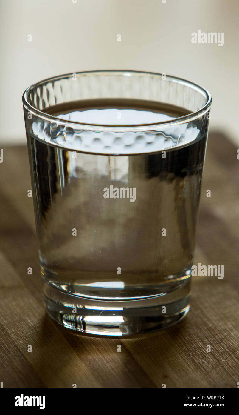 Close up d'un verre d'eau sur le tapis en bois rayé utilisé. Banque D'Images