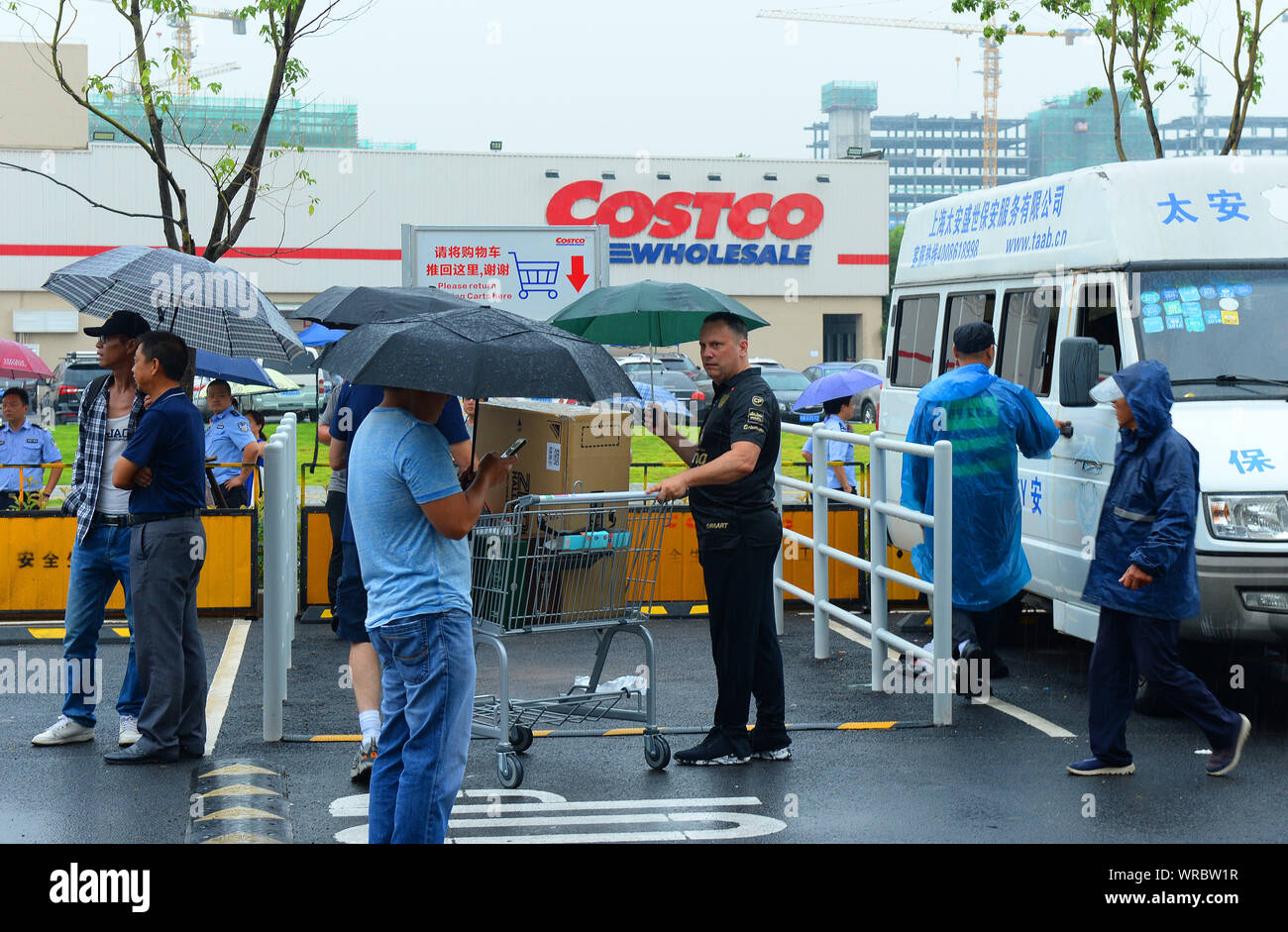 Les gens attendent sous la pluie devant le magasin Costco à Shanghai, en  Chine, le 29 août 2019. Costco, le géant américain de la chaîne de vente au  détail, a annoncé qu'il limitait ses achats à 2000 par jour dans son  premier magasin chinois après avoir ...