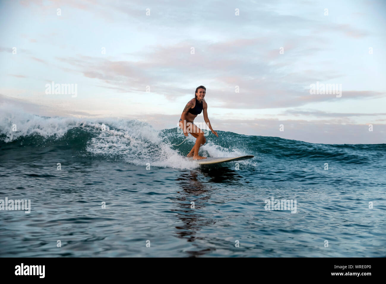 Jeune femme surf au lever du soleil Banque D'Images