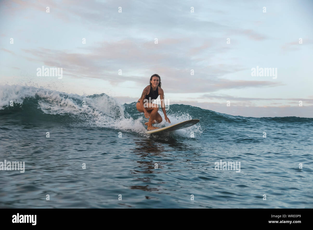Jeune femme surf au lever du soleil Banque D'Images