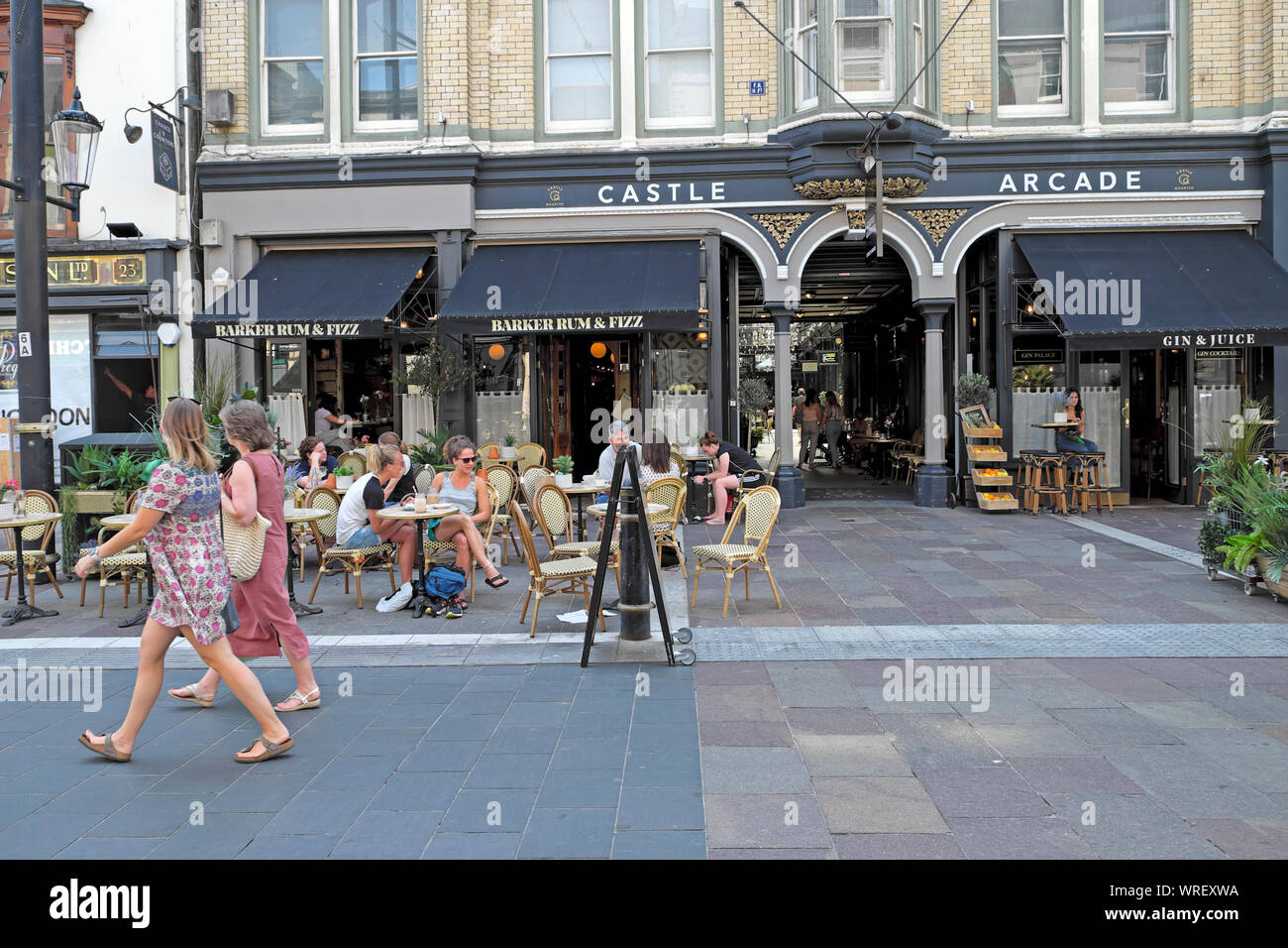 Les femmes en marche en dehors de la rue St Mary Castle Arcade & des gens assis à des tables à l'extérieur de Barker Rum & Fizz le centre-ville de Cardiff au Pays de Galles UK KATHY DEWITT Banque D'Images