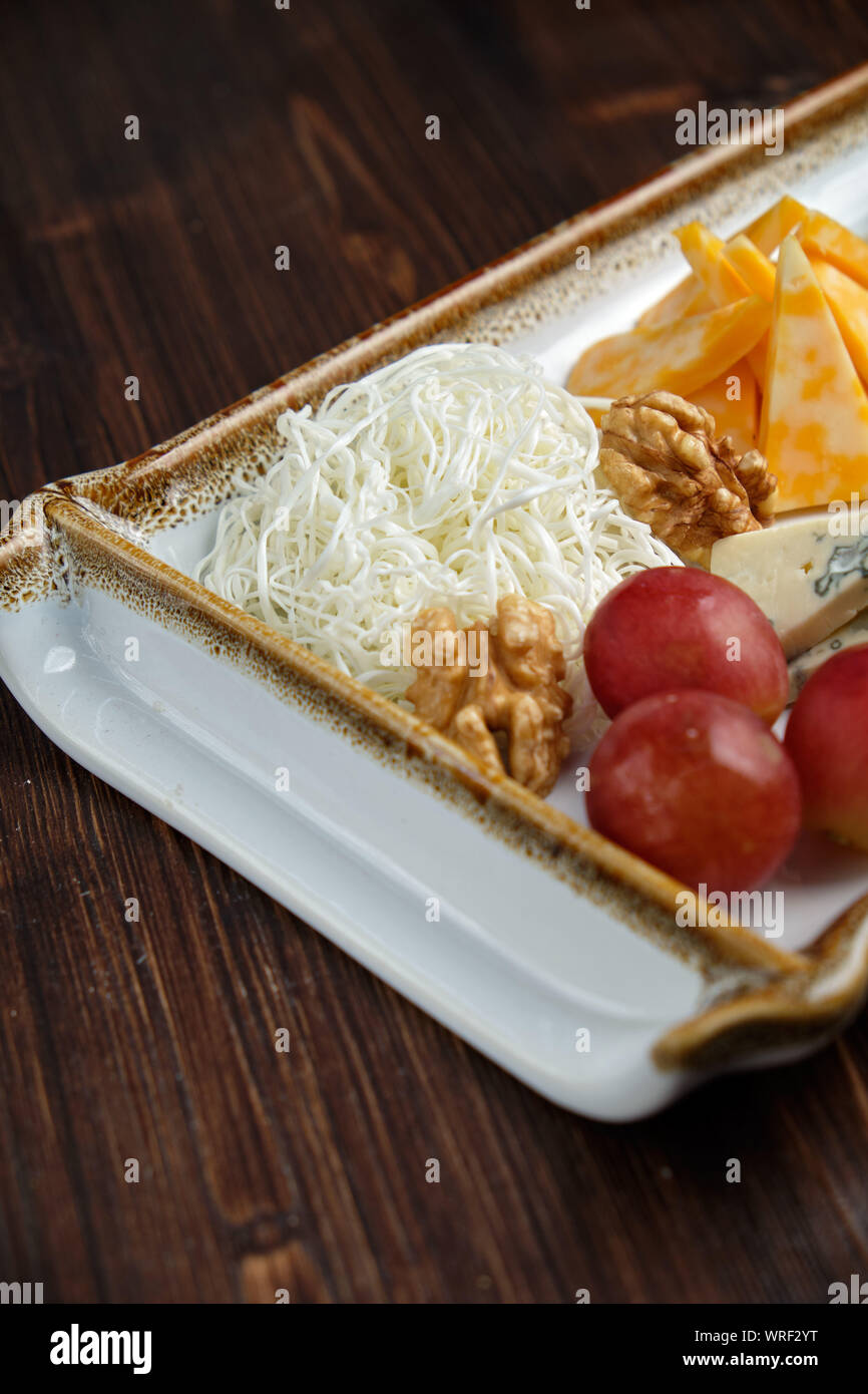 Belle table assiette de fromage sur une plaque blanche sur fond sombre.Close up, vue du dessus. Style alimentaire. Restaurant menu Banque D'Images