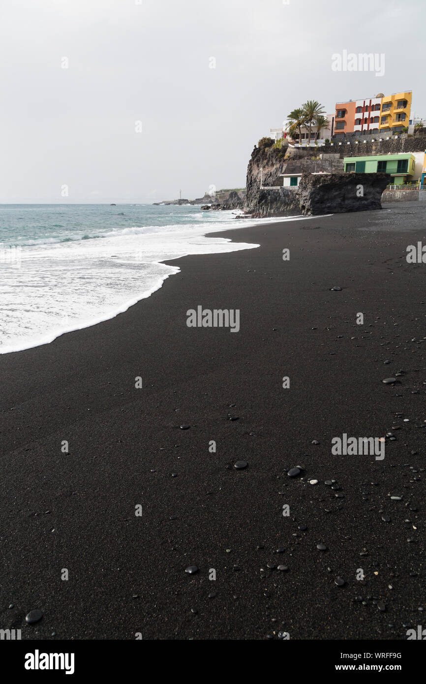 Des vagues à la plage de sable noir de Puerto Naos à La Palma, Espagne avec le village en arrière-plan. Banque D'Images