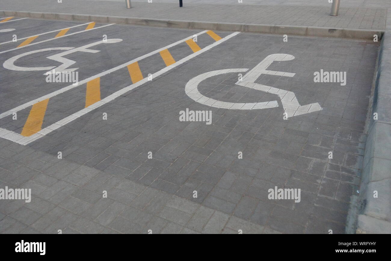 Parking réservé pour les personnes physiquement handicapées pour un stationnement commercial public avec des lignes blanches et jaunes Banque D'Images