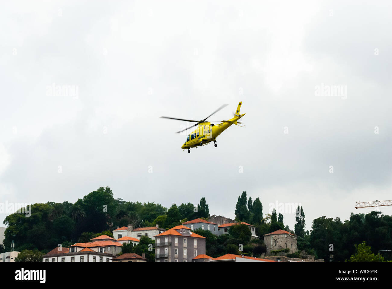 PORTO, PORTUGAL - 18 juin 2014 : Un hélicoptère de l'INEM air ambulance prend son envol au-dessus du fleuve Douro à ciel couvert. Banque D'Images