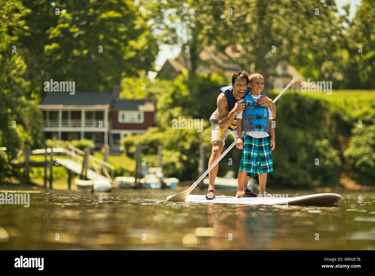 Père et fils s'amusant paddleboarding sur la rivière. Banque D'Images