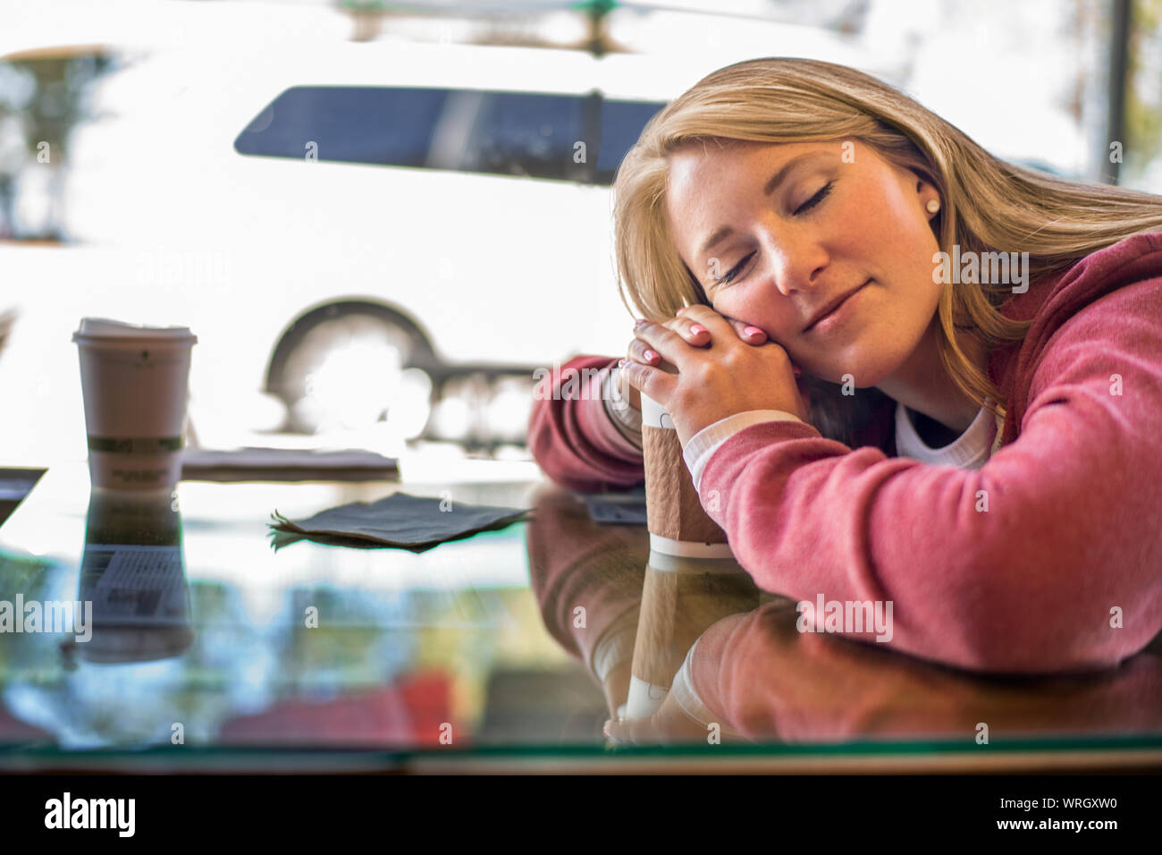 Assez jeune femme posant sa tête sur son café. Banque D'Images
