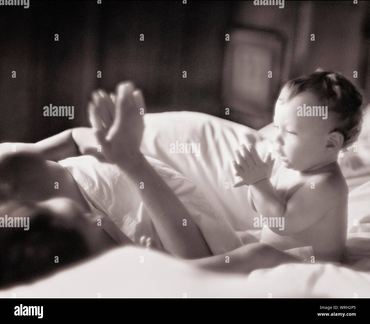 Une mère enseigne à son fils une comptine en position allongée sur un lit. Banque D'Images