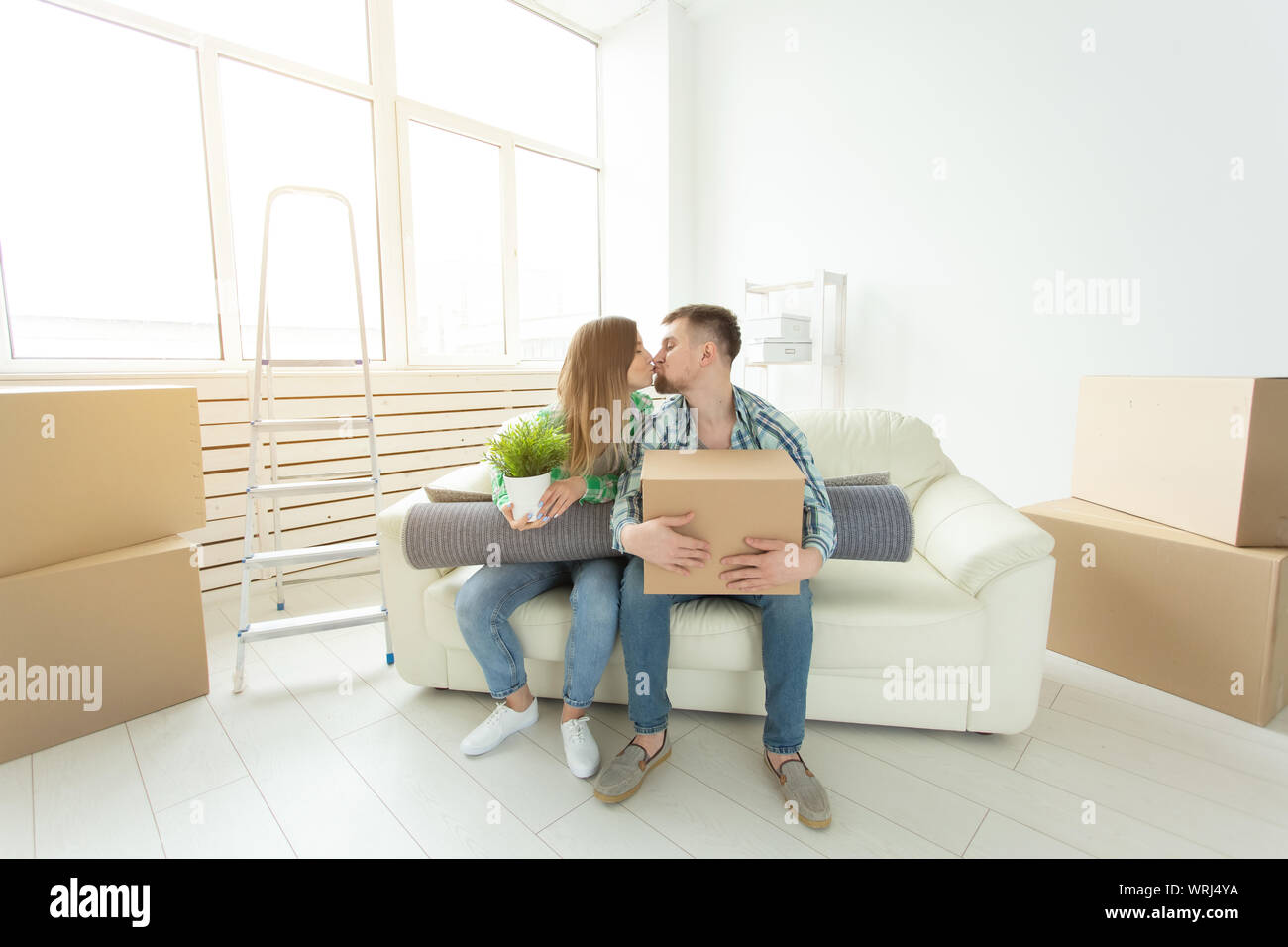 Déménagement et concept immobilier - Happy couple on sofa dans leur nouvel appartement Banque D'Images