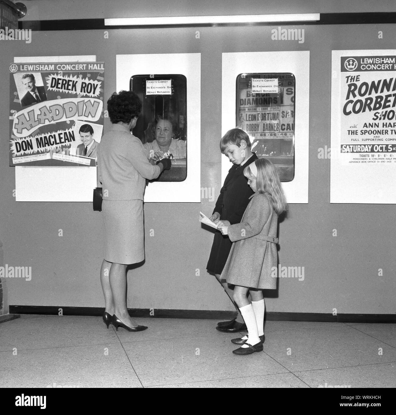 Années 1970, historiques, une mère avec ses deux enfants, l'achat de billets pour une pantomine, 'Aladdin' fixant Derek Roy et Don MacLean à la salle de Concert de Lewisham, Lewisham, Londres, Angleterre, Royaume-Uni. Il offre également à la salle de concert, 'Le Ronnie Corbet Show. Banque D'Images