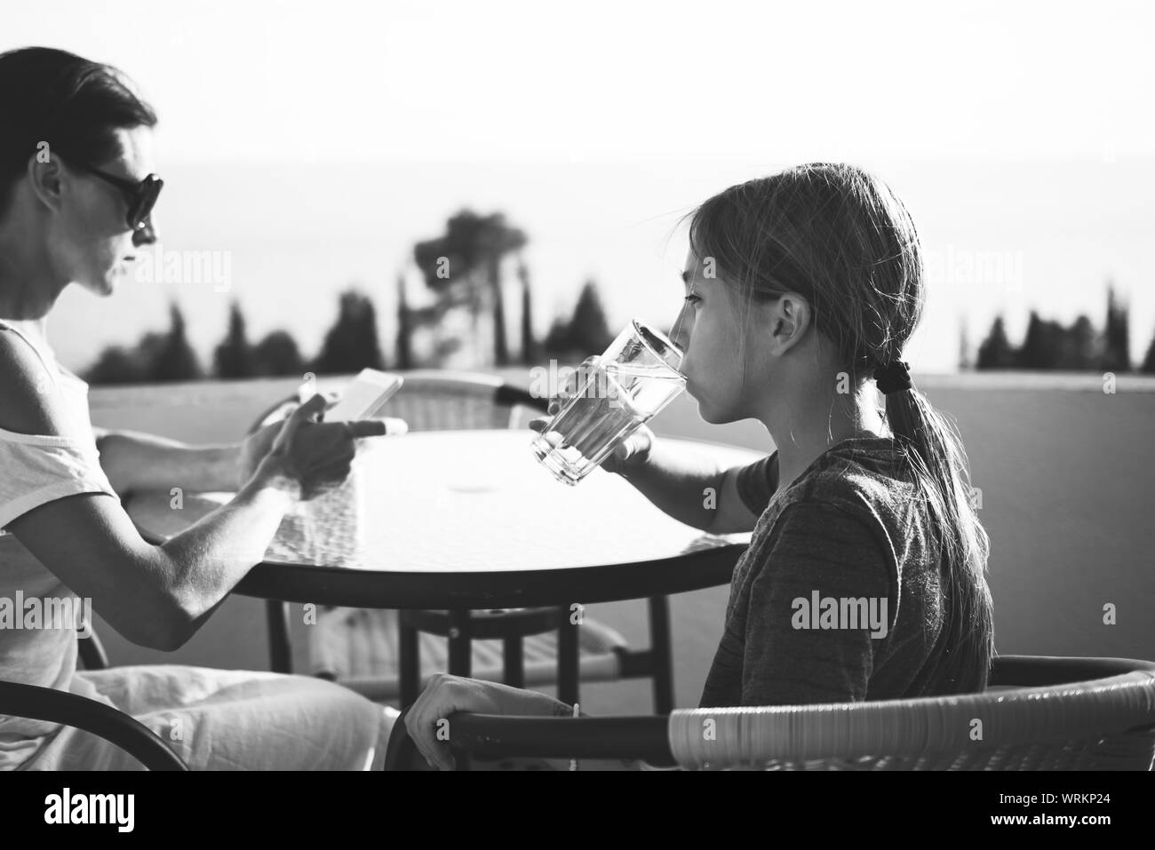 Fille assise sur le balcon avec sa mère et l'eau potable Banque D'Images