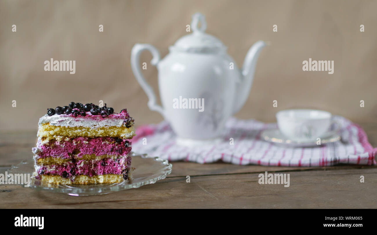 Morceau de gâteau aux bleuets sur table en bois avec tasse de thé en arrière-plan. Banque D'Images