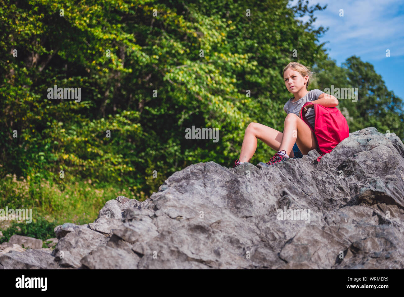 Fille assise sur un rocher et à la distance au repos Banque D'Images