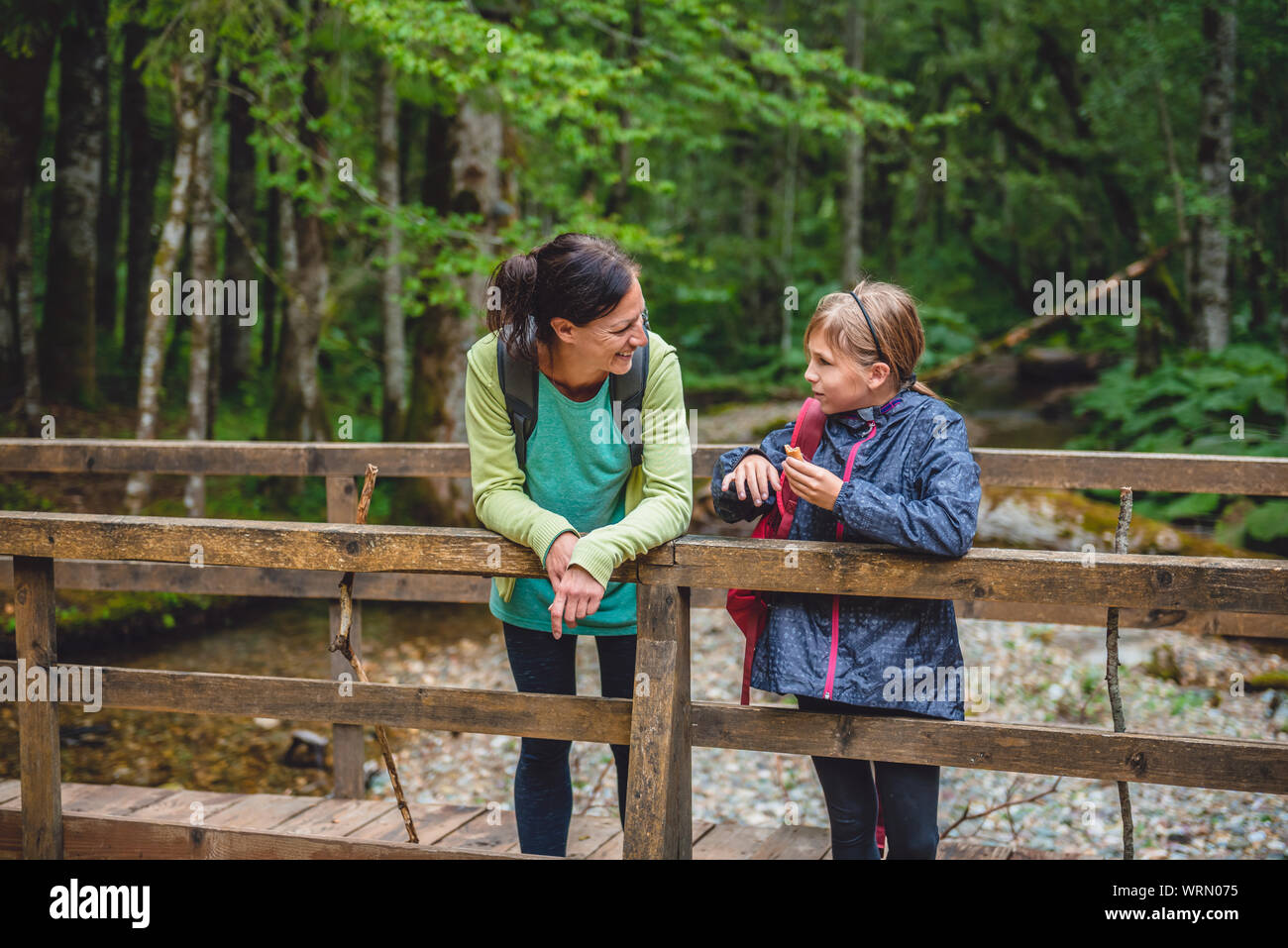 Mère et fille avec chien reposant sur le pont de bois dans la forêt de la montagne Banque D'Images Mère et fille avec chien reposant sur le pont de bois dans la forêt de la montagne Banque D'Images