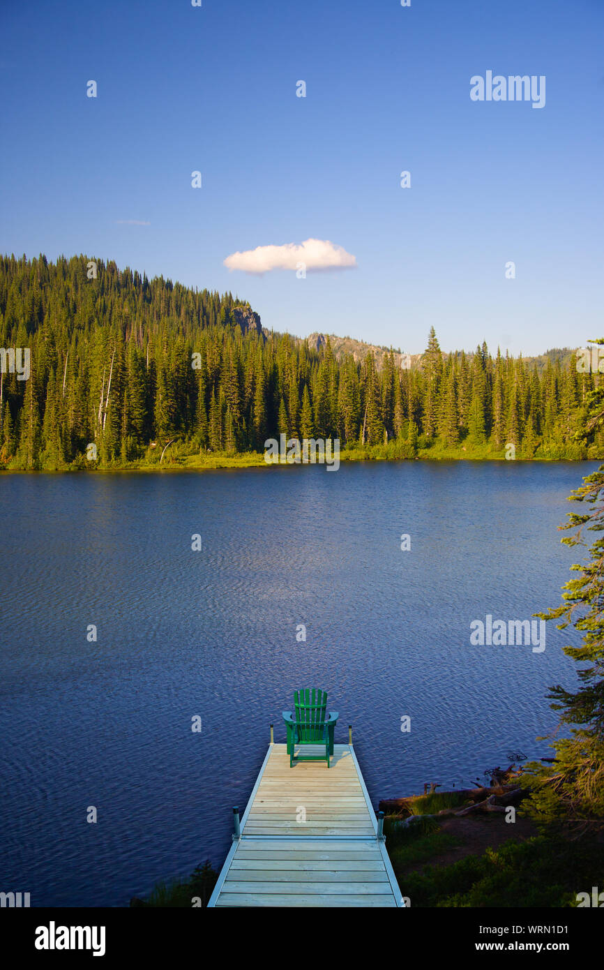 Image manipulée numériquement d'une chaise adirondack assis sur un quai avec un lac à l'arrière-plan. Banque D'Images