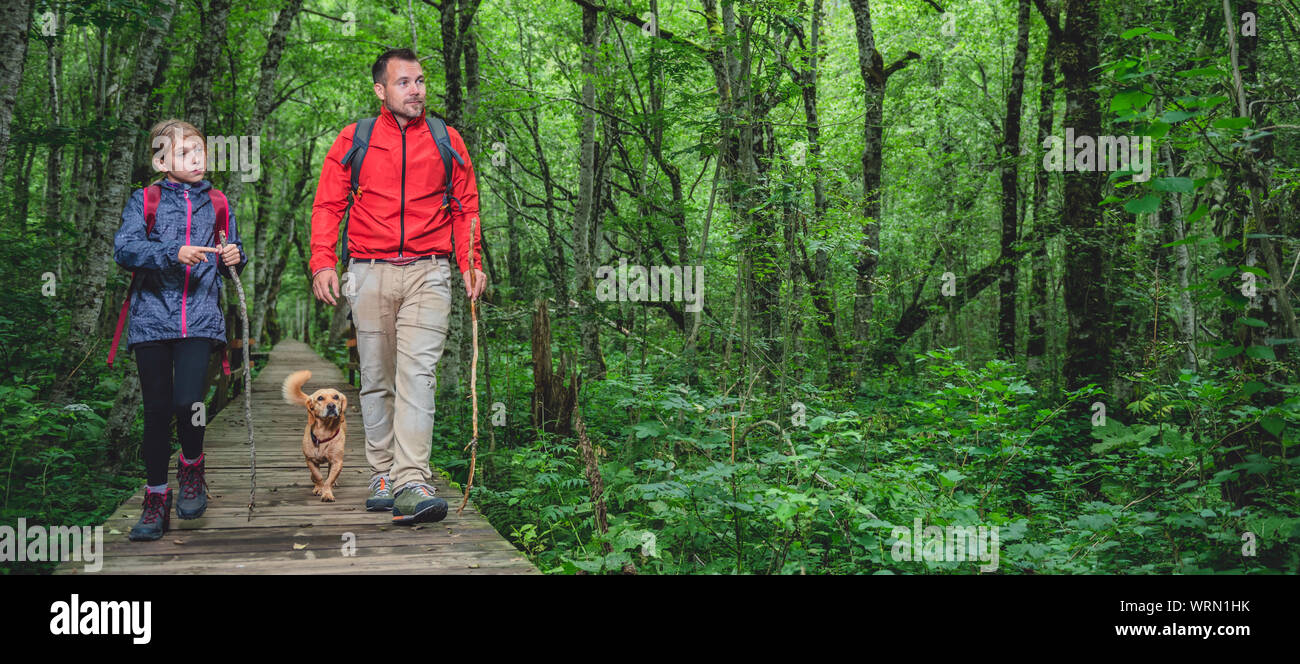 Père et fille avec petit chien jaune de la randonnée sur un sentier en forêt Banque D'Images Père et fille avec petit chien jaune de la randonnée sur un sentier en forêt Banque D'Images