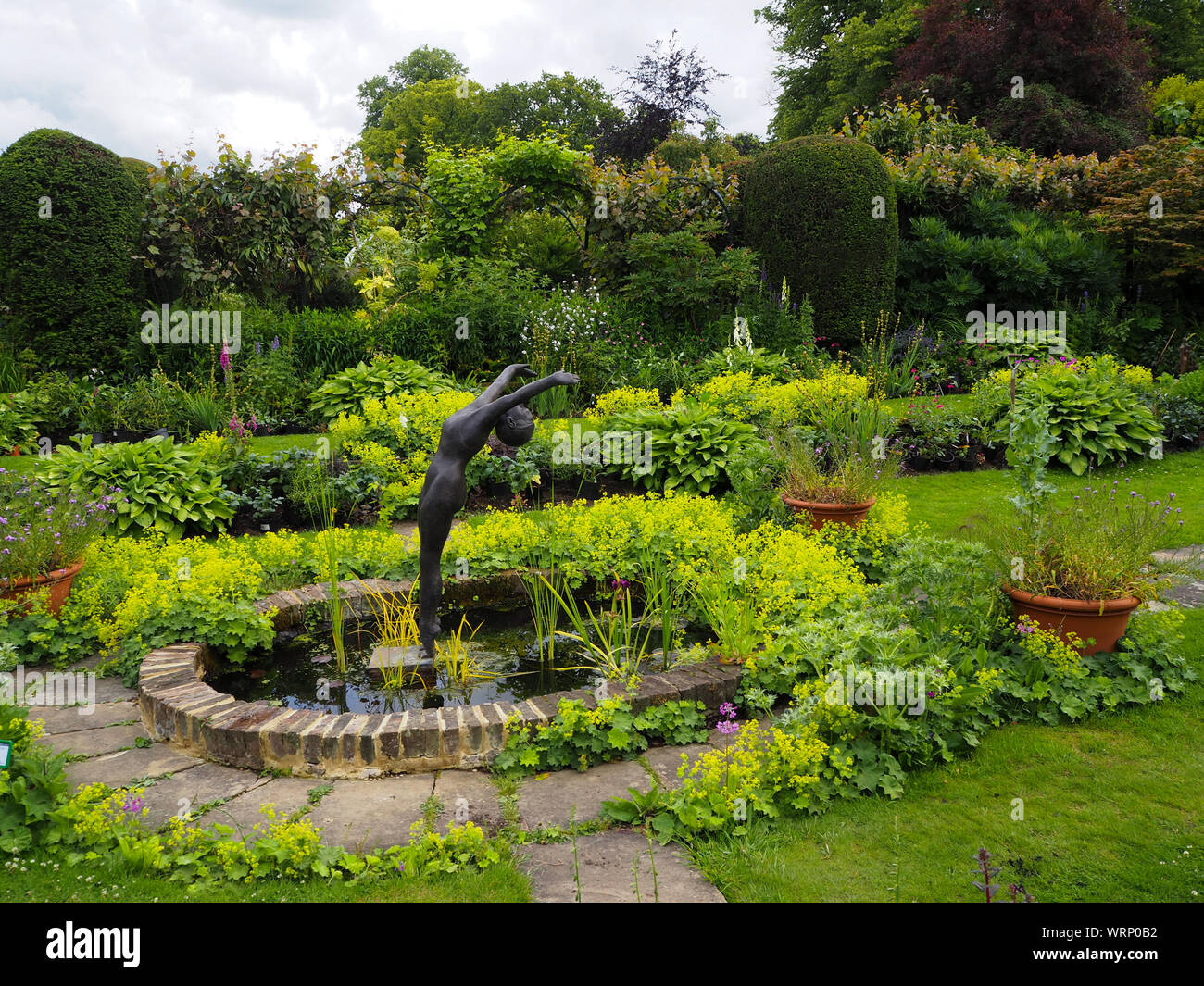 Chenies Manor sunken garden bassin d'ovale, les frontières et l'usine mitoyenne sculpure de plongeur par Alan Biggs encadré de feuillage vert luxuriant et haies, Banque D'Images