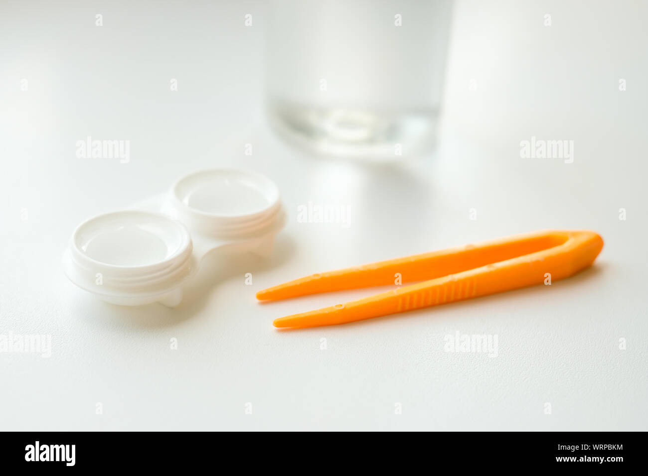 Accessoires pour une utilisation correcte des lentilles de contact : boîtier, brucelles et flacon de solution sur fond blanc. Correction de la vision en toute sécurité. Mise au point sélective. Banque D'Images