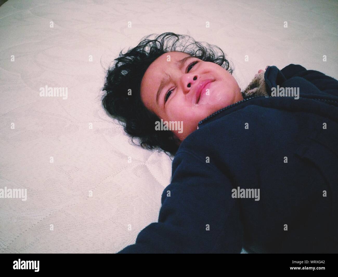 Portrait Of Boy Crying On Bed Banque D'Images