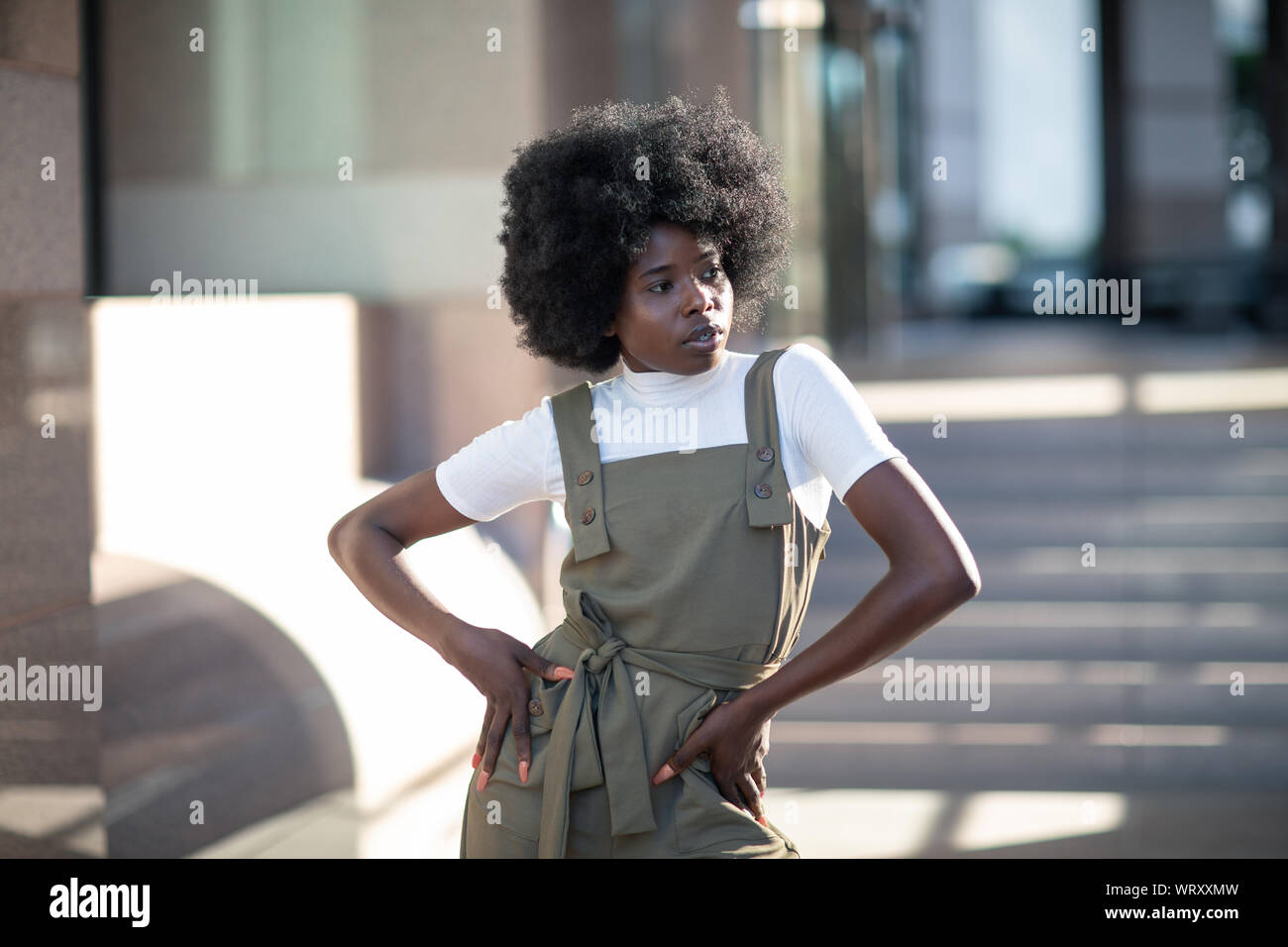 Belle African American girl avec les cheveux bouclés, la mode des bretelles, et col roulé blanc. Banque D'Images