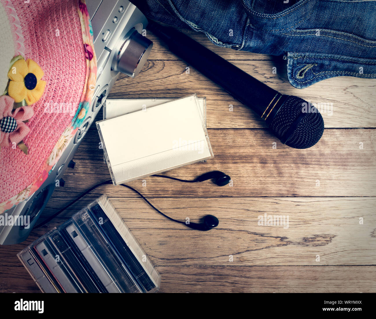 Ensemble d'appareil audio, microphone, écouteurs, cd, sac à main en jean et chapeau de paille sur fond en bois vintage. Banque D'Images
