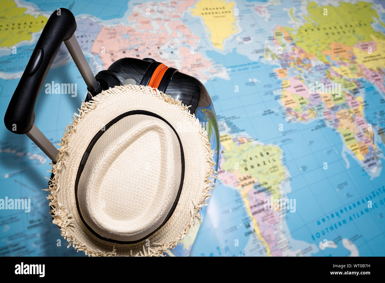 Concept de voyage, sac de voyage avec chapeau de paille sur la carte du monde sous la lumière du soleil Banque D'Images