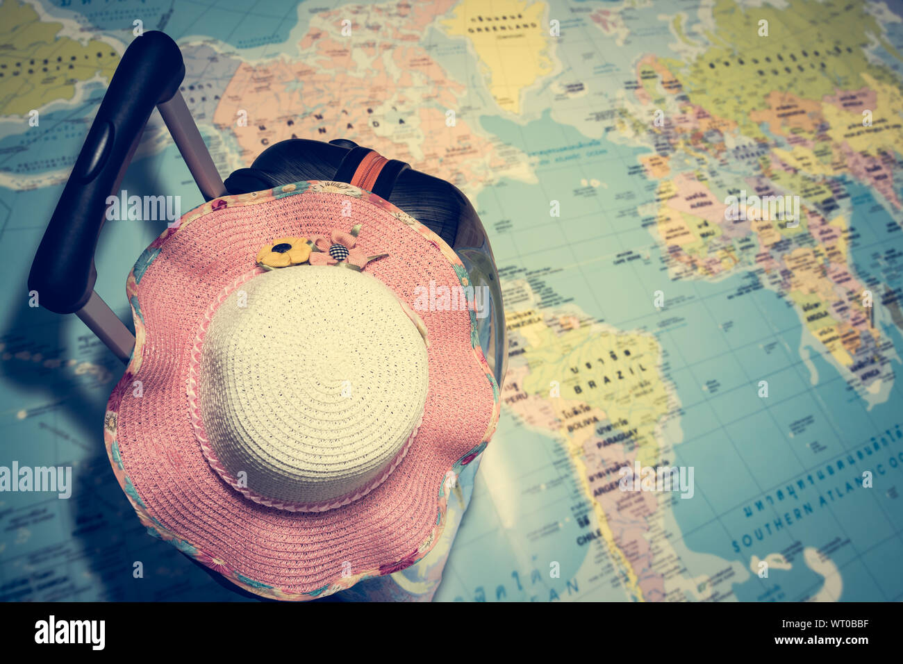 Concept de voyage, sac de voyage avec femme Chapeau de paille sur la carte du monde sous la lumière du soleil Banque D'Images