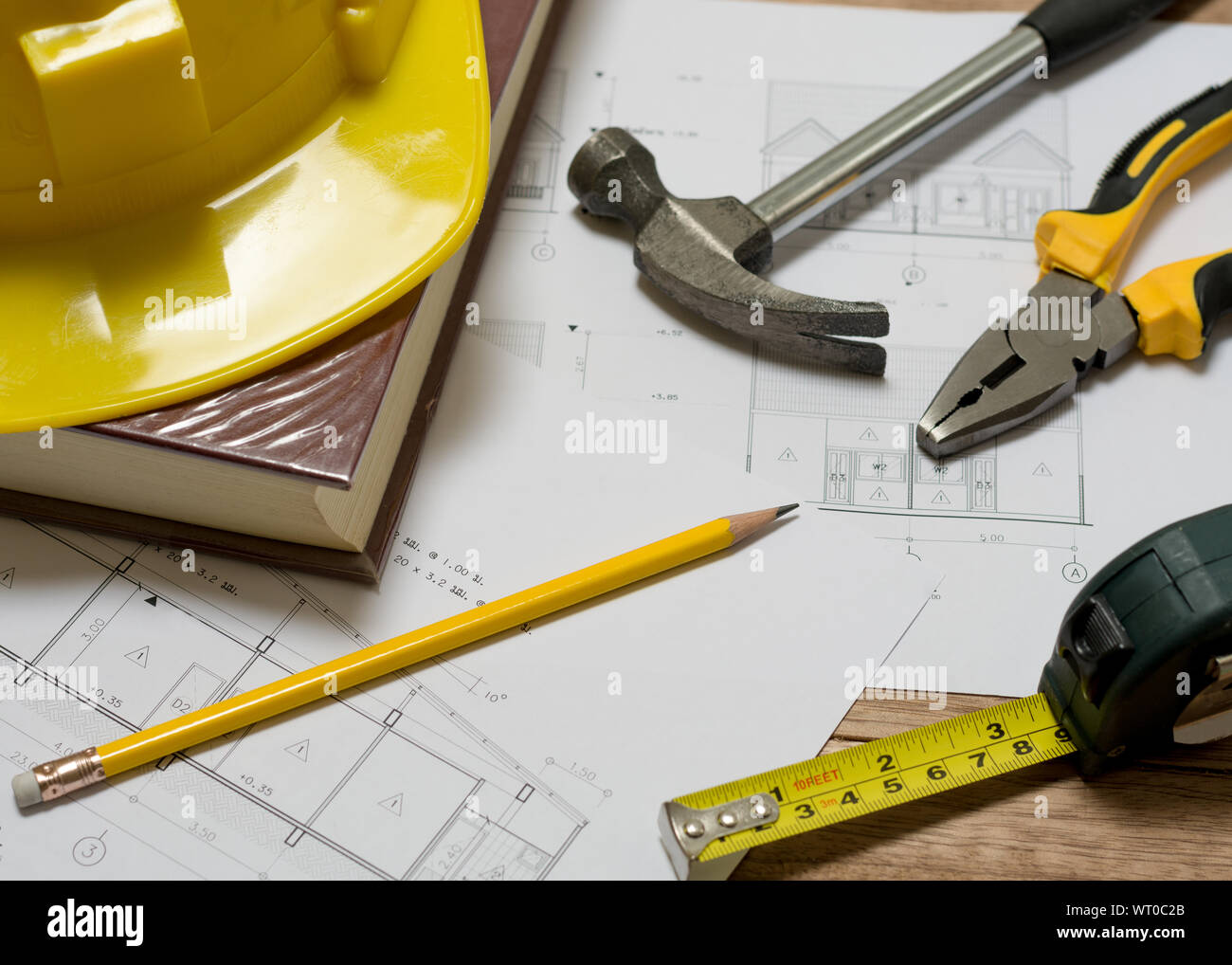 Plan de construction avec casque de construction, livre, marteau, crayon, outil de mesure et d'une pince sur la table en bois Banque D'Images