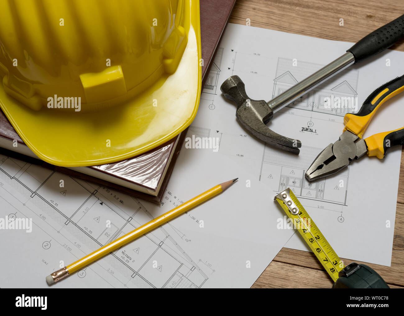 Plan de construction avec casque de construction, livre, marteau, crayon, outil de mesure et d'une pince sur la table en bois Banque D'Images