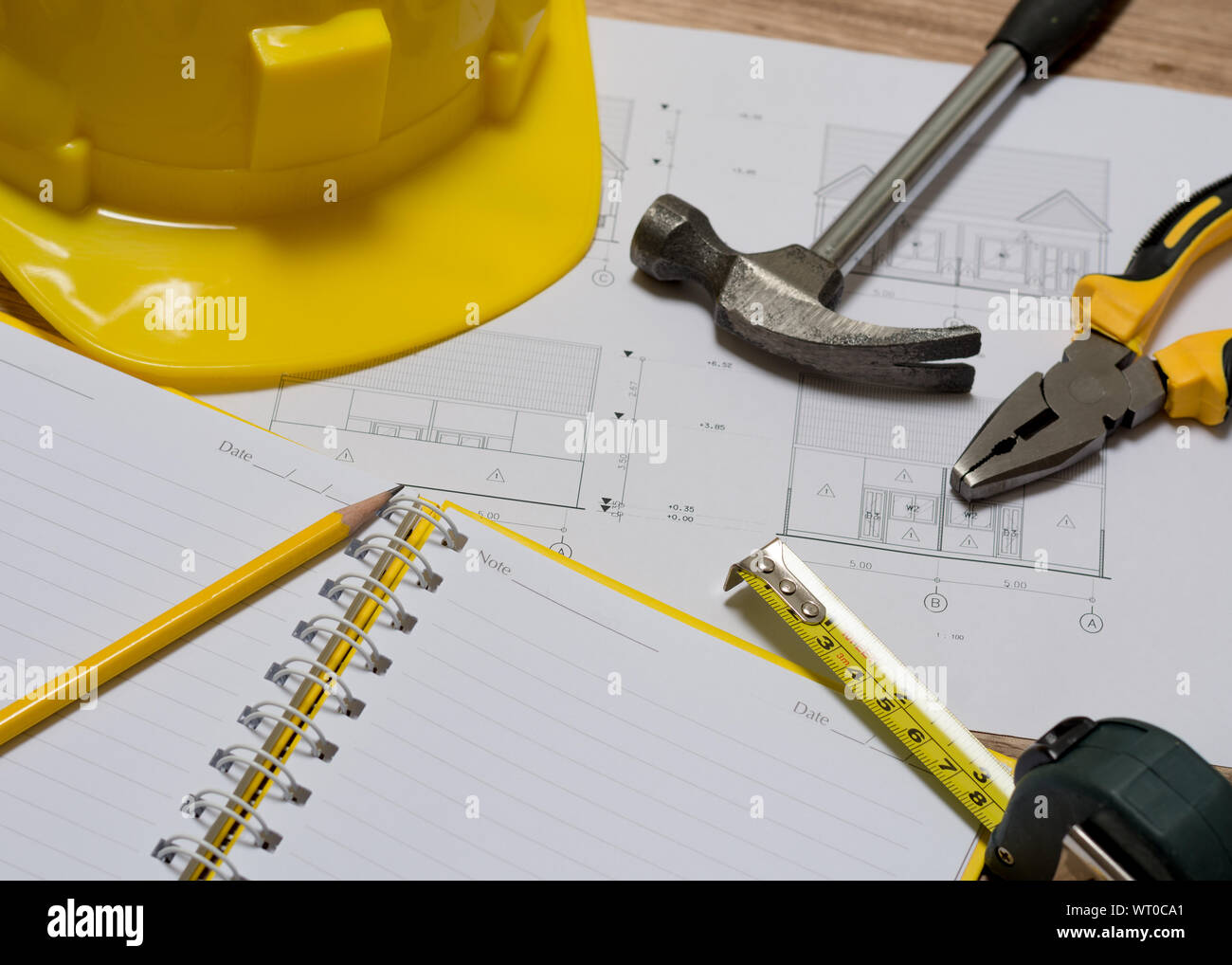 Plan de construction avec casque de construction, portable, marteau, crayon, outil de mesure et d'une pince sur la table en bois Banque D'Images