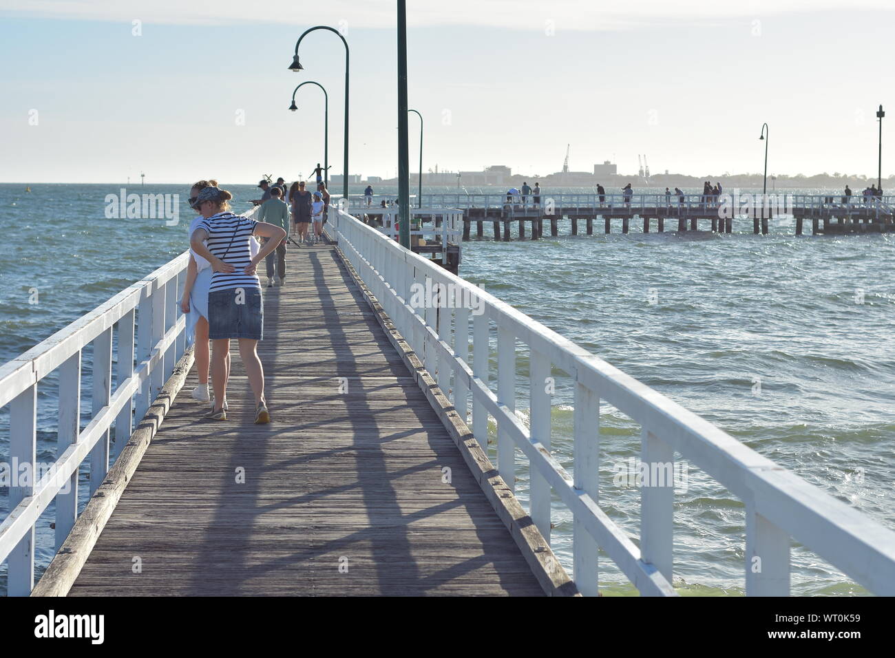 Les gens qui marchent et se reposer sur les anciens quais industriels avec plancher en bois et garde-fous dans la baie de Port Phillip. Banque D'Images