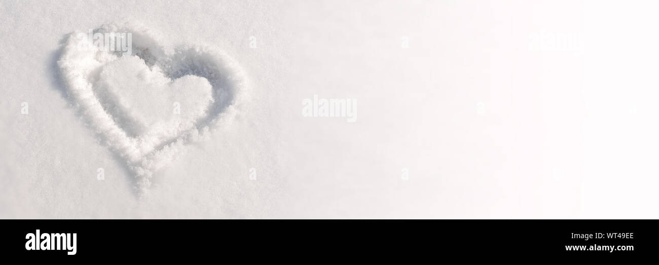 De près de l'encombrement d'un cœur dans la neige, l'arrière-plan d'hiver panoramique Banque D'Images