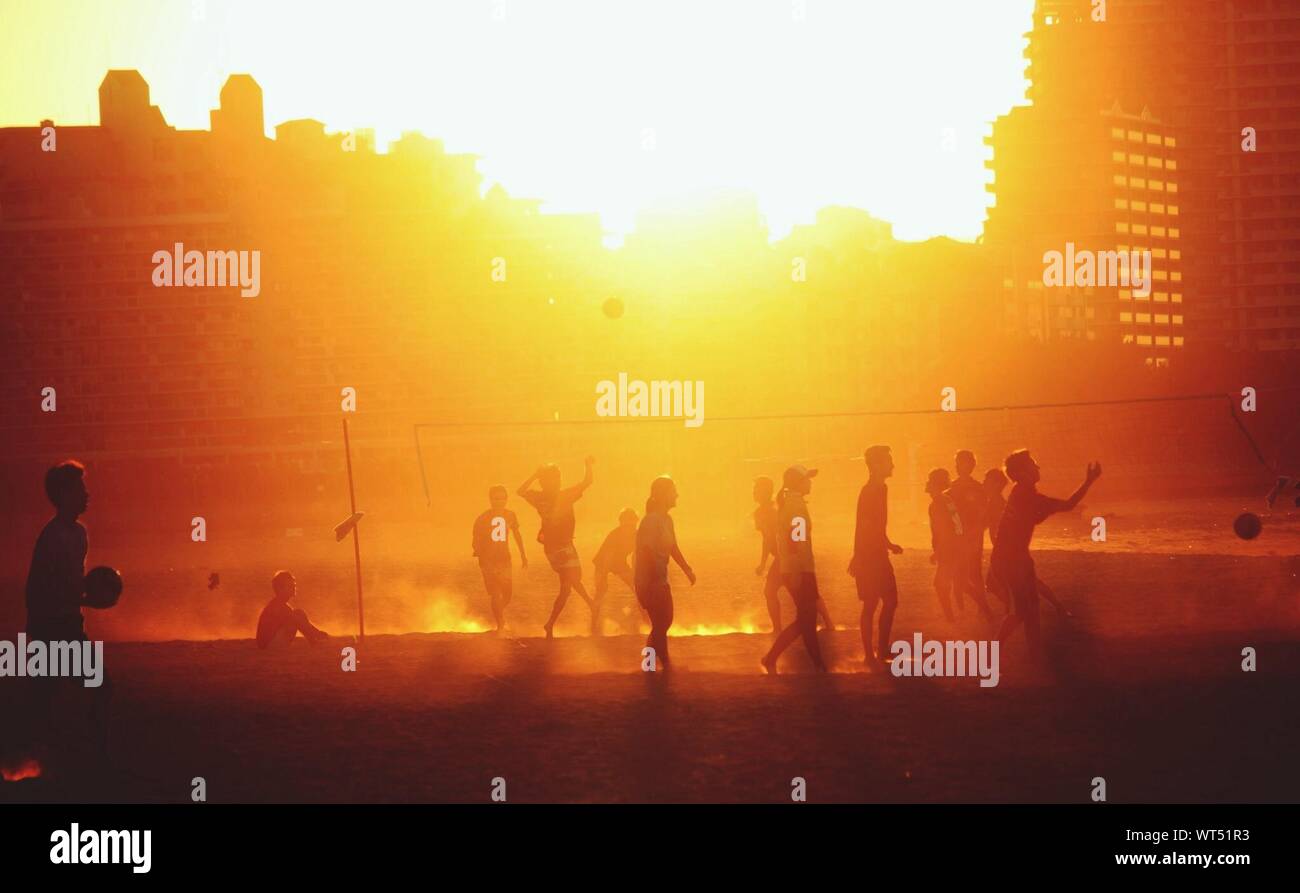 Les gens à jouer au volleyball de plage au coucher du soleil Banque D'Images