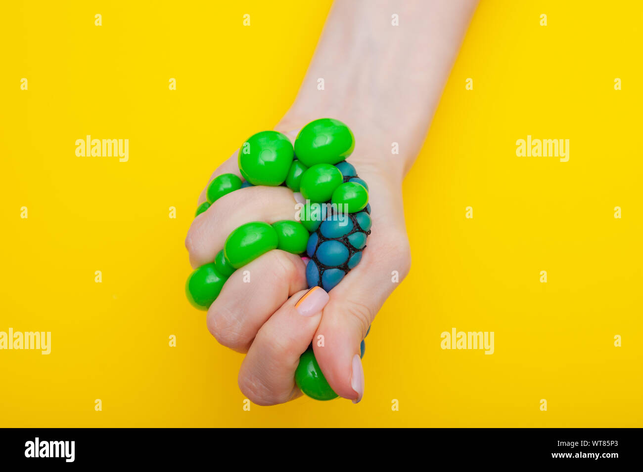 Close-up. Jouet anti-stress dans la main des femmes sur fond jaune Banque D'Images