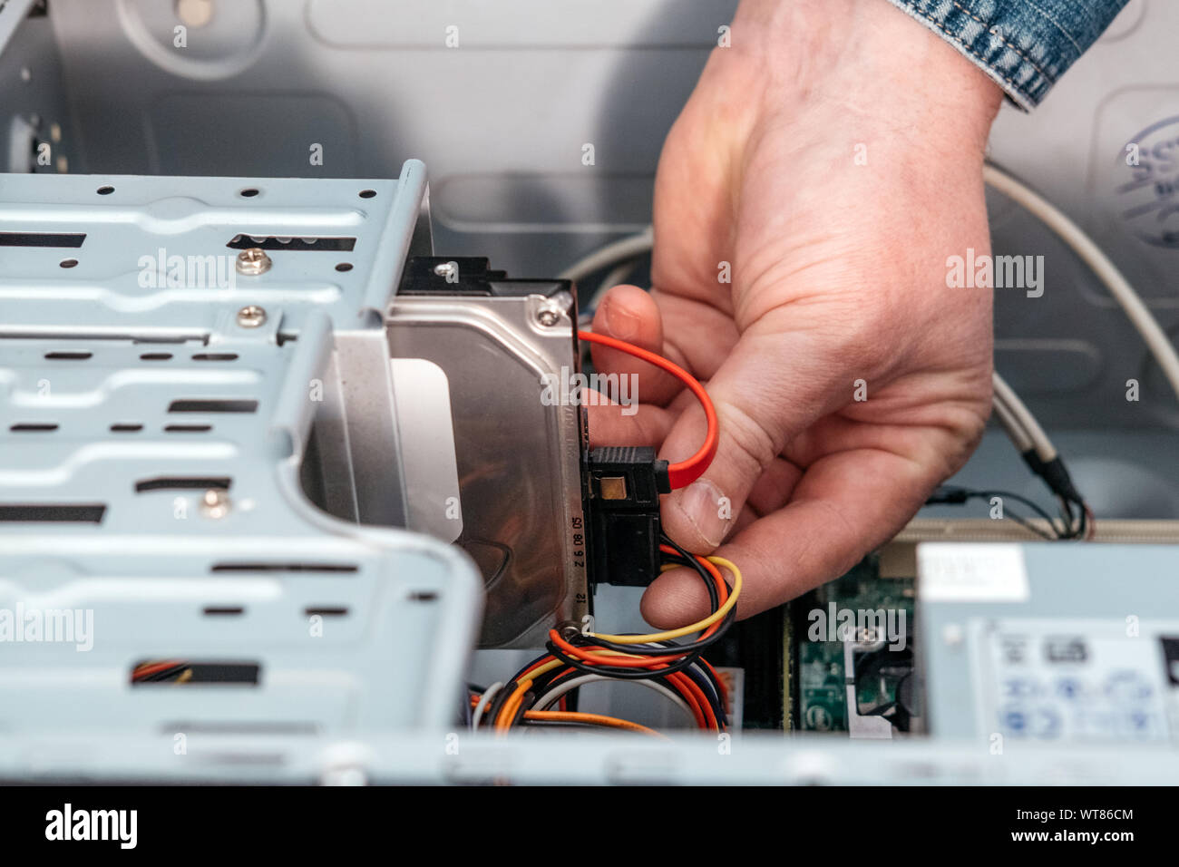 Main de l'homme branché à l'interface SATA (Serial ATA), l'accessoire câble de données série dans disque dur. Interface de bus d'ordinateur pour connecter les périphériques de stockage de masse, Banque D'Images