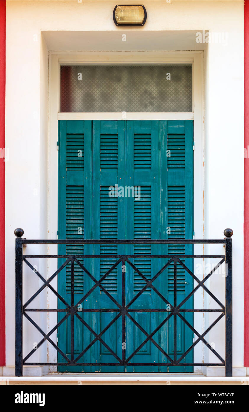 Les portes de balcon en bois avec des volets en bois avec des grilles métalliques du balcon, encadrée sur la façade le long du périmètre rouge avec rayures verticales. Banque D'Images