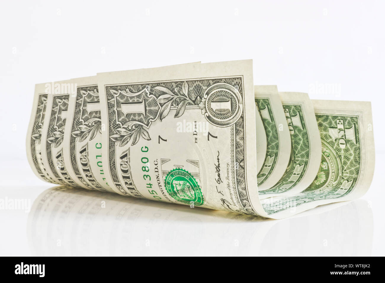 Un peu gondolé un dollars sur un fond clair de près. Notes de réflexion sur une surface brillante. Banque D'Images
