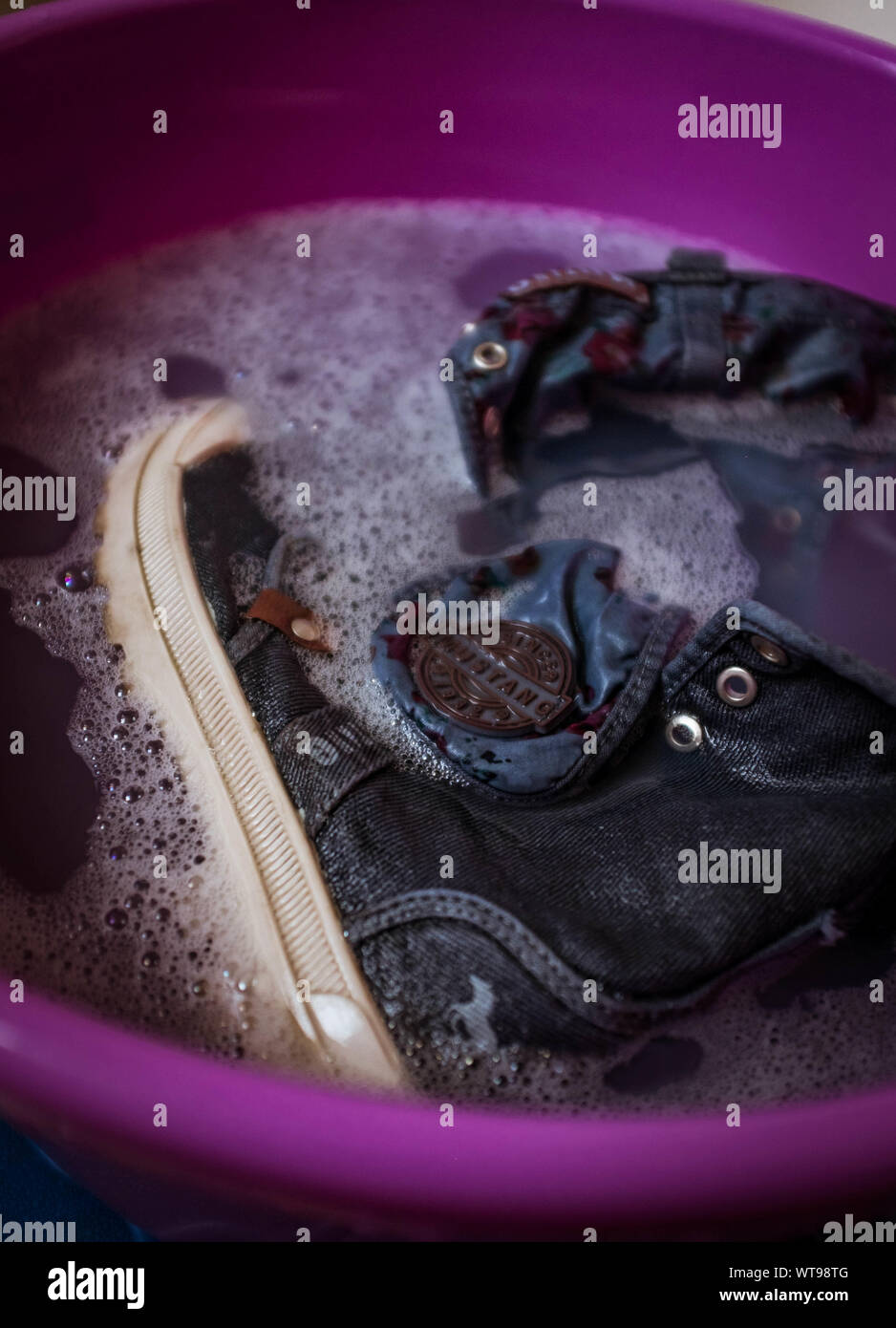 Une paire de chaussures de trempage dans de l'eau savonneuse. Banque D'Images