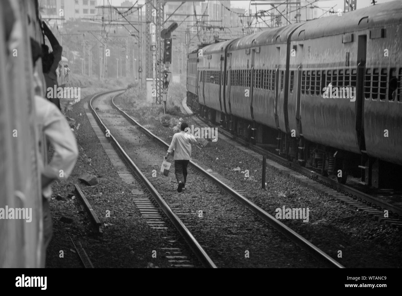 Homme marchant dans le chemin de fer de Mumbai parler au téléphone mobile Banque D'Images