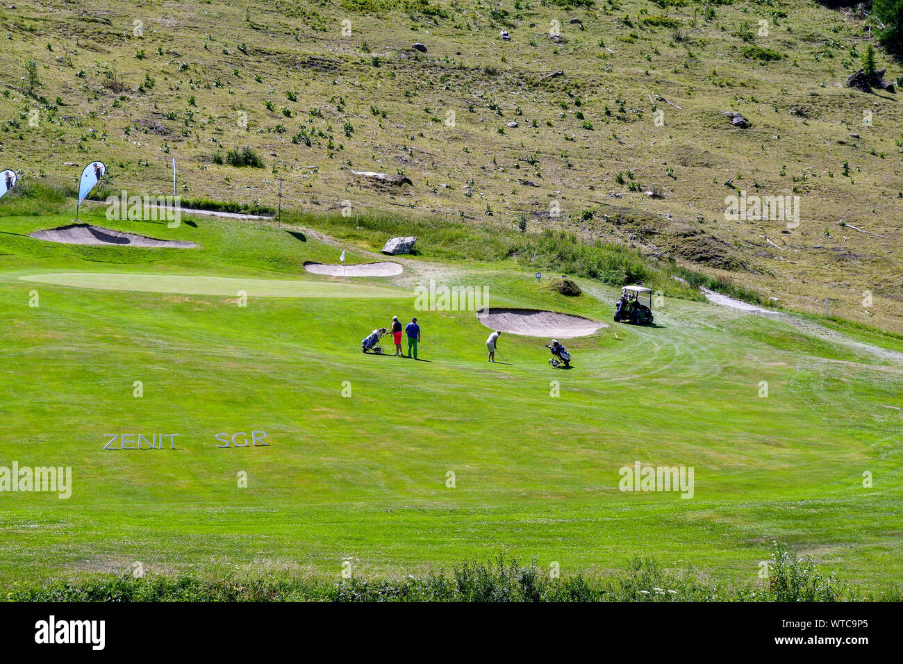 Vue panoramique sur un parcours de golf de montagne avec les golfeurs jouant dans un beau jour d'été, Golf Club Courmayeur, Val Ferret, Courmayeur, vallée d'aoste, Italie Banque D'Images