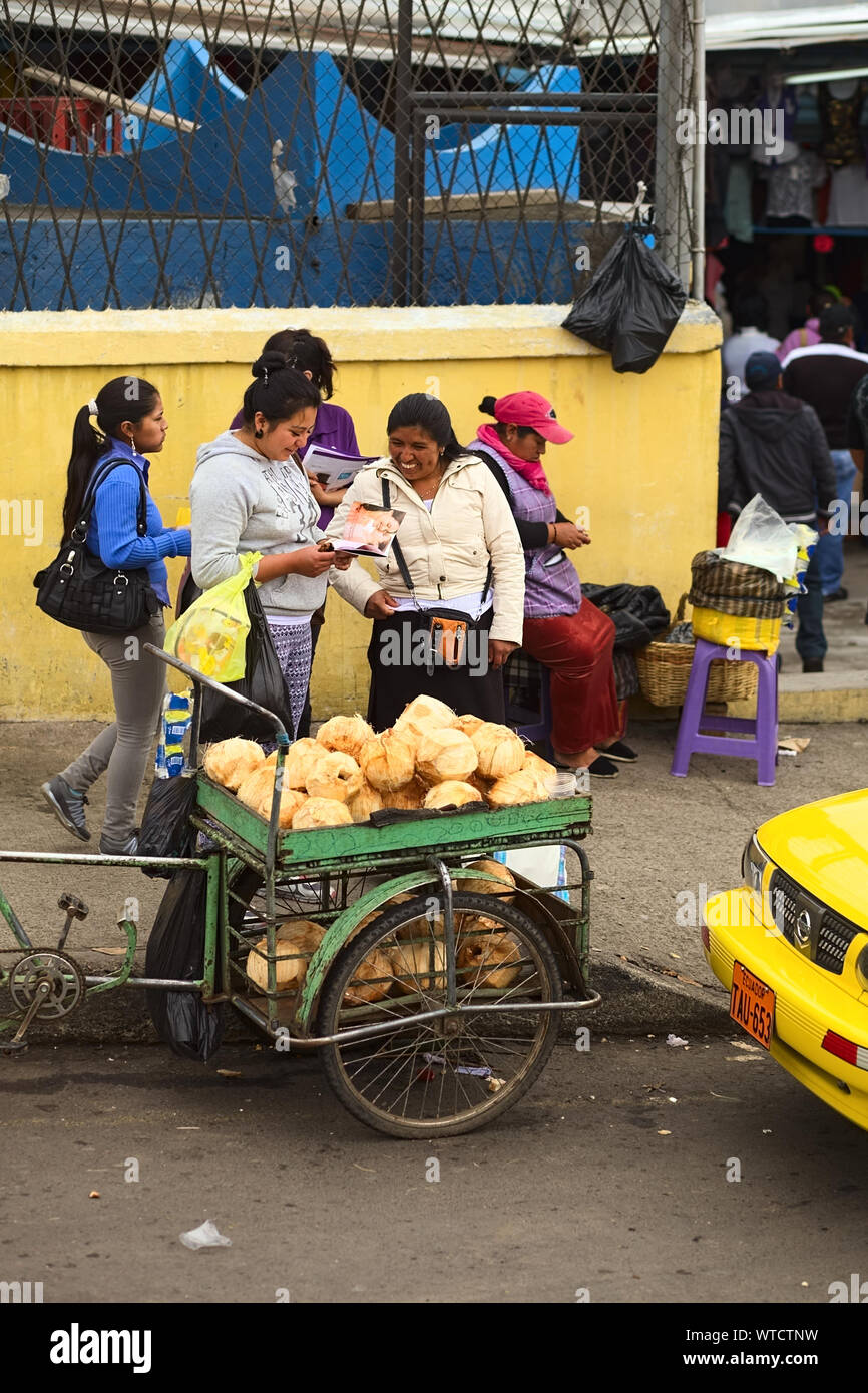 AMBATO, ÉQUATEUR - 12 MAI 2014 : personnes non identifiées sur le trottoir avec un petit panier de noix de coco sur le bord de la route le 12 mai 2014 à Ambato, Équateur. Banque D'Images