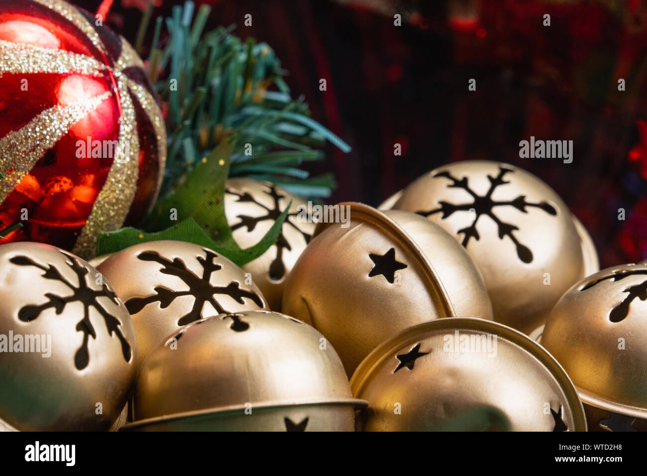 Close up of a bowl full of golden Jingle Bell avec un motif flocon et un rouge avec gold glitter ball ornement en selective focus with copy space Banque D'Images