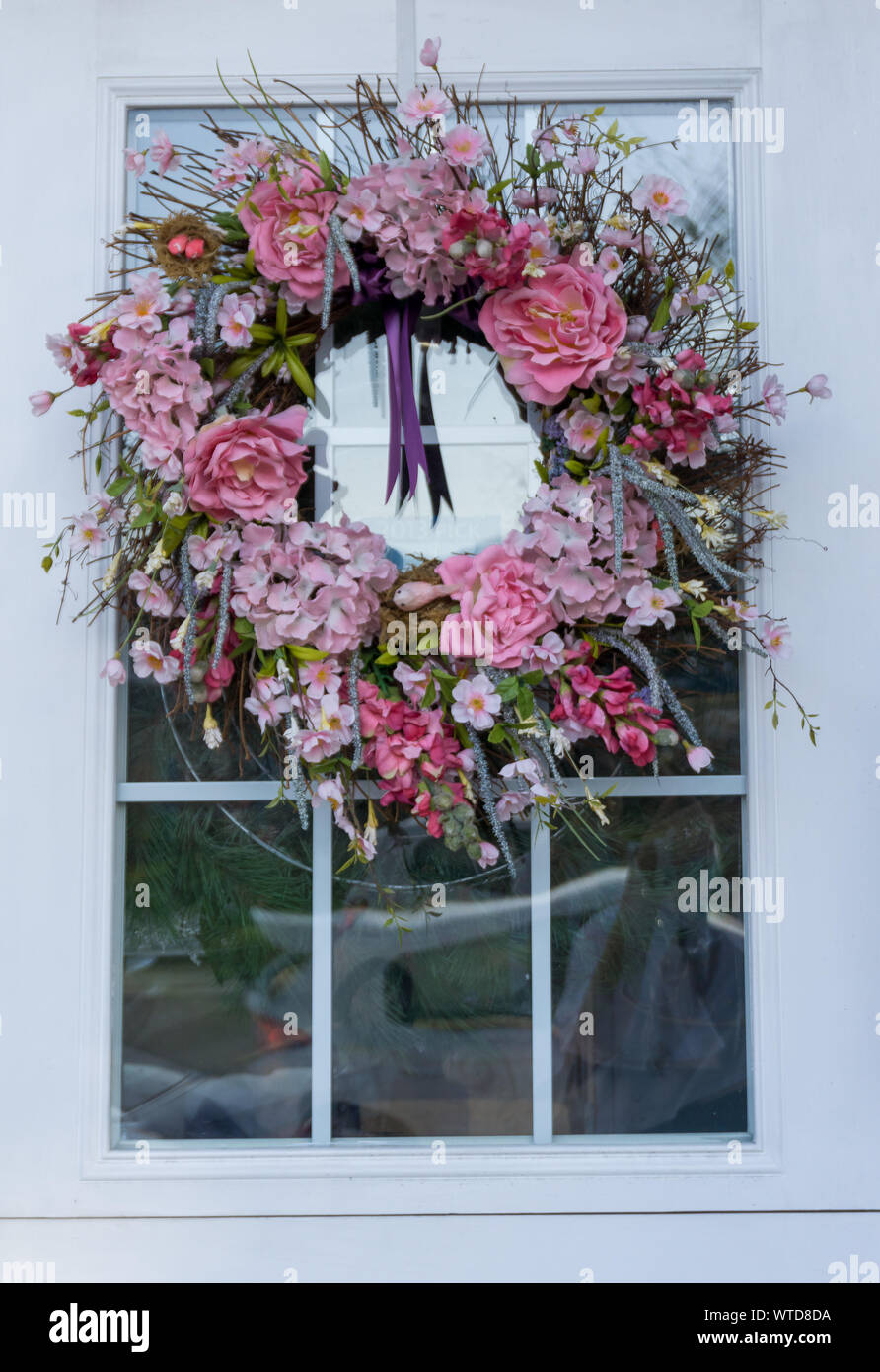 Une couronne faite de fleurs rose accroché sur la porte Banque D'Images